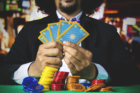 Businessman gambling with poker cards and stack of chip on the table in the casinoの写真素材