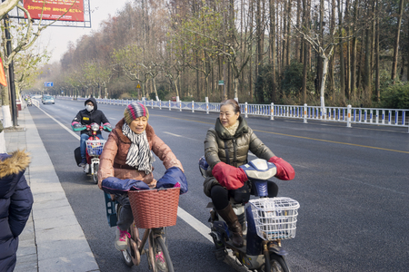 HANGZHOU, China. April 18, 2017: Elderly chinese women rides bicycle on the West Lake street in Hangzhou, Chinaのeditorial素材