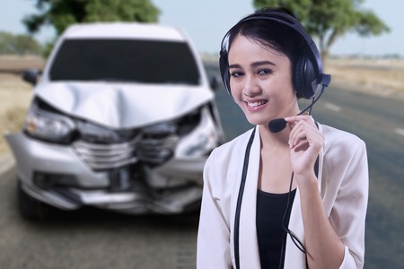 Picture of a beautiful female operator wearing a headphone while helping a broken car in an accident