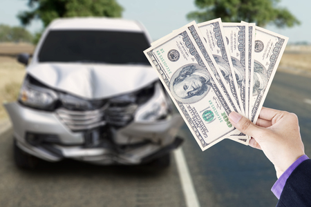 Hands of businessman holding currency dollars with a broken car in the highwayの写真素材