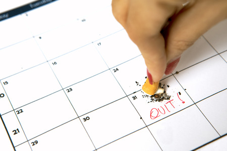 Woman hand destroying a cigarette on calendar with quit wordの写真素材