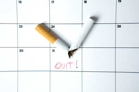 Broken cigarette above calendar date with quit wordの写真素材