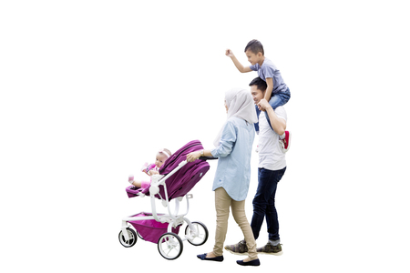 Image of young Muslim mother carrying baby in the stroller with her husband holding a boy, isolated on white backgroundの写真素材