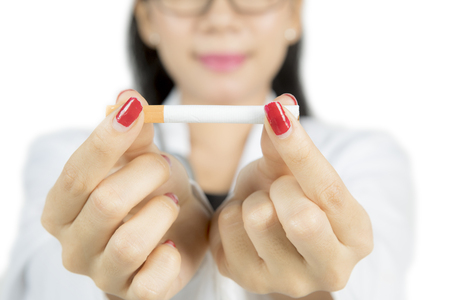 Close up of female doctor hand holding a cigarette, isolated on white backgroundの写真素材