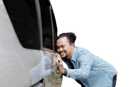 Young afro man looking new car while smiling at the car, isolated on white backgroundの写真素材
