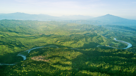 Beautiful aerial view of mountain valley with a village, river, and green forest. Shot at Majalengka, West Java, Indonesiaの写真素材