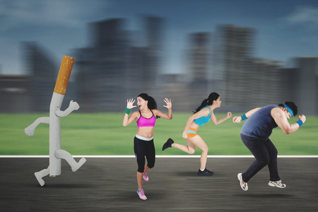 Image of runners chased by a cigarette while running in the roadの写真素材