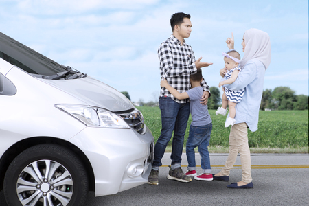 Image of Asian family arguing while standing near a car with their children on the roadsideの写真素材