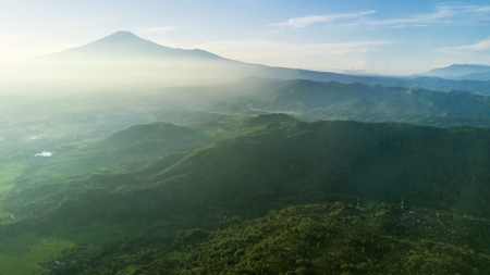 Beautiful aerial view of mountain scenery in the misty morning with green forest. Shot in Majalengka, West Java, Indonesiaの写真素材