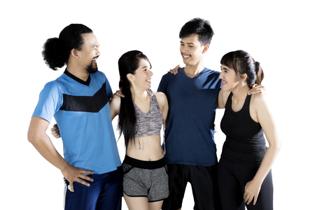 Multiracial group of sports people laughing together while standing in studio, isolated on white backgroundの写真素材