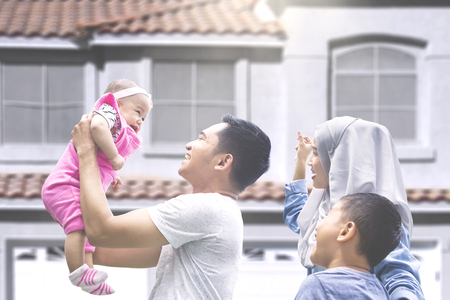 Two muslim parents playing with their baby and son at new house outsideの写真素材