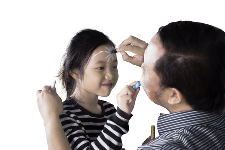 Little girl and her father playing with crayons while painting on a face each other, isolated on...