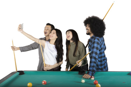 Group of happy multiracial people taking a selfie photo together next to pool table, isolated on...