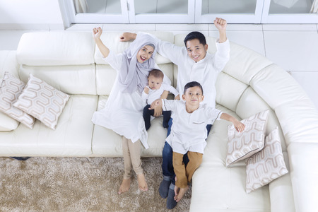 Top view of muslim family expressing their happiness while sitting on the sofa togetherの写真素材