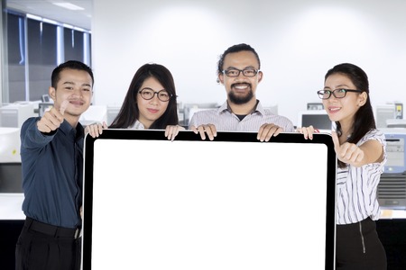 Group of multiracial businesspeople showing thumbs up while holding a blank placard in the officeの写真素材