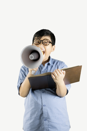Portrait of boy student is reading book while using a megaphone, isolated on white backgroundの写真素材