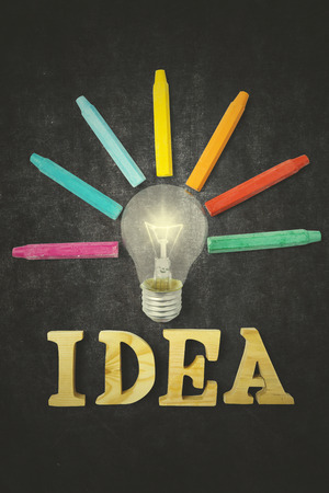 Colorful crayons and lightbulb with idea word on the chalkboardの写真素材