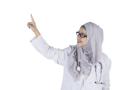 Picture of young Muslim female doctor touching something while standing in the studioの写真素材