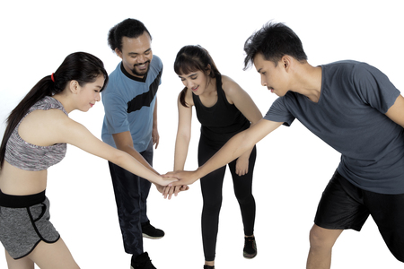 Group of healthy multiracial people joining hands together in a circle while wearing sportswear before workout. Isolated on white backgroundの写真素材