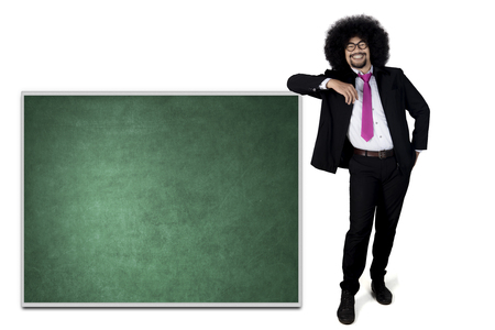 Portrait of Afro businessman smiling at camera while leaning on the chalkboard isolated on white backgroundの写真素材