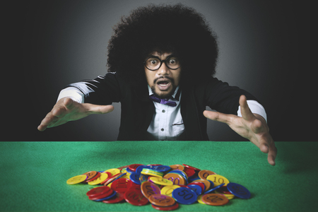 Portrait of desperate Afro man with curly hair, losing casino chip in gamblingの写真素材