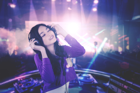 Image of pretty DJ enjoying her song while playing music in the nightclubの写真素材