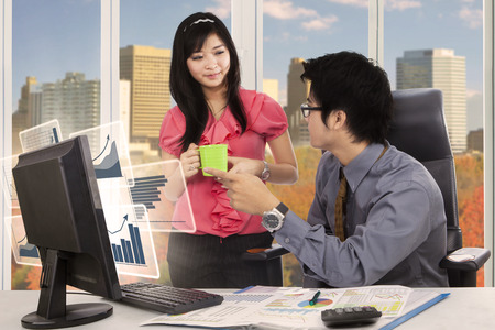 Picture of two business teams discussing financial statistics while working with a computer and paperwork on the deskの写真素材