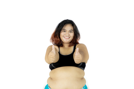 Photo of fat woman wearing sportswear while showing thumbs up at the camera, isolated on white backgroundの写真素材