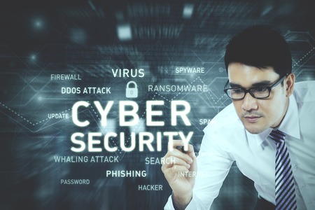 Picture of young businessman wearing glasses while writing a text of cyber security on the virtual...
