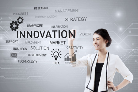 Photo of a beautiful businesswoman writing a word about innovation on the virtual screenの写真素材