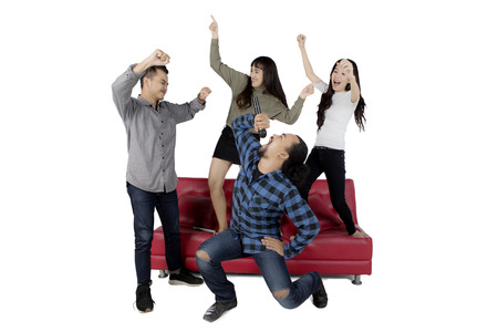 Group of happy multiracial friends dancing and singing together at karaoke, isolated on white backgroundの写真素材
