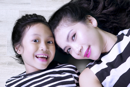 Image of pretty woman with her daughter smiling at the camera while taking a picture togetherの写真素材