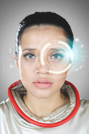 Portrait of futuristic woman looking at the camera with a virtual hologram in her eyesの写真素材