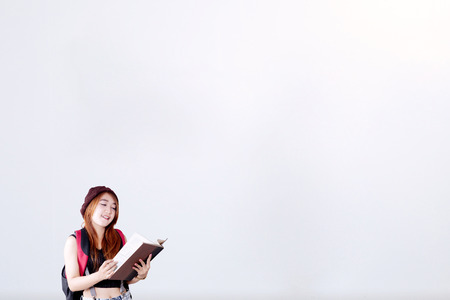 Photo of a female high school student wearing casual clothes while reading a book, shot with copy space on the wallの写真素材