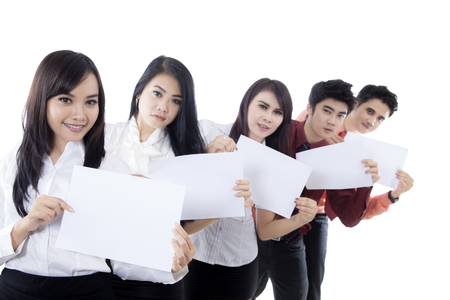 Young business team showing empty papers and looking at the camera, isolated on white backgroundの写真素材