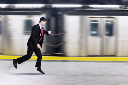 Picture of Italian businessman checking his watch while rushing for a train with fast motion blurの写真素材