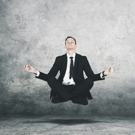 Image of American male manager wearing a formal suit while levitating during doing meditationの写真素材