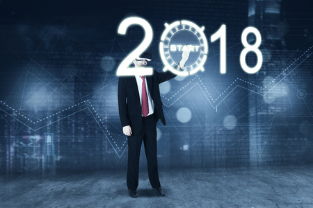 Full length of young businessman using a virtual reality glasses while touching a start button with numbers 2018 in the futuristic screen の写真素材