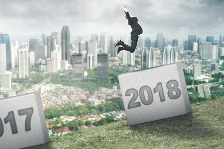Picture of European businessman jumping to number 2018 in the stone. Shot on the hill