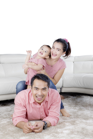 Portrait of young parents playing with their baby while laughing together at homeの写真素材