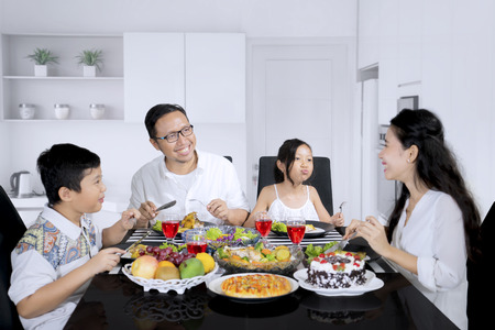 Picture of young family looks happy while eating meals and sitting in the kitchenの写真素材