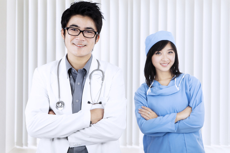 Portrait of happy medical team smiling at camera while arms crossed and standing in the hospitalの写真素材