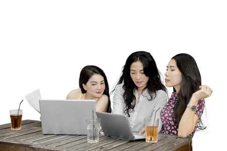 Image of three female students sitting together while studying with laptop, isolated on white backgroundの写真素材