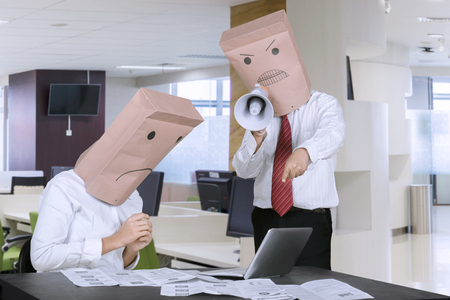 Picture of unidentified businessman scolding his employee by using a megaphone in the officeの写真素材