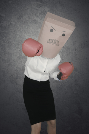 Photo of an anonymous female worker wearing boxing gloves while punching at the cameraの写真素材