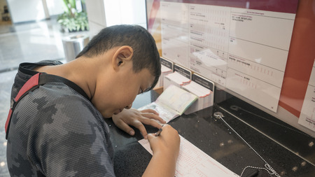 Singapore. November 06, 2017: Asian kid filling up immigration form at customs service area in airportのeditorial素材