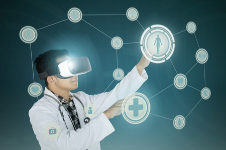 Medical doctor wearing virtual reality glasses while touching medical buttons on the futuristic...