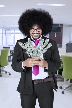 Happy afro businessman making money onlineの写真素材