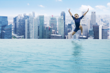 JAKARTA - Indonesia. December 26, 2017: Little child jumping into a swimming pool on the rooftop of hotel in Jakartaの写真素材