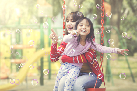 Asian mother and daughter having a quality time playing bubbles at playgroundの写真素材